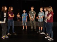 grupa dziewcząt i chłopców stojących na proscenium