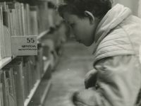 chłopiec szukający książek w bibliotece