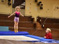 Dziewczynka skaczącą na batucie i przyglądająca się temu Instruktorka