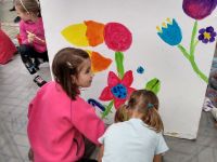 dzieci malujące kwiaty na białym kubiku