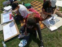 dzieci malujące prace siedzące na trawie