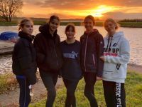 grupa dziewcząt na tle jeziora i zachodzącego słońca
