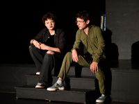 dwoje aktorów siedzących na brzegu sceny