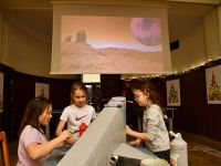 Trzy dziewczynki malują statek kosmiczny wykonany z tektury