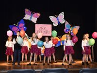 grupa dziewcząt na scenie z balonami śpiewające piosenkę