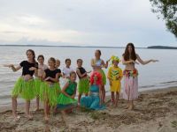 uczestniczki obozu tańczące nad jeziorem w hawajskich spódniczkach